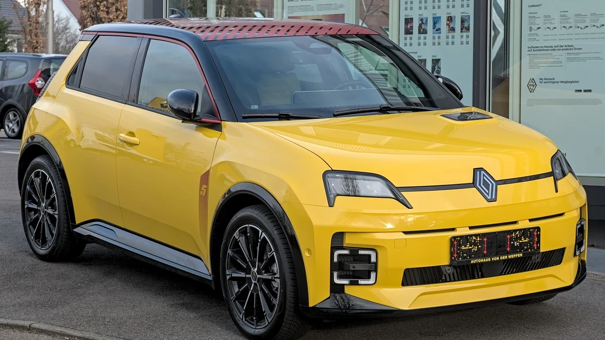 Жълт Renault 5 E-Tech Electric, заснет отпред и отстрани на паркинг пред автосалон през зимата.